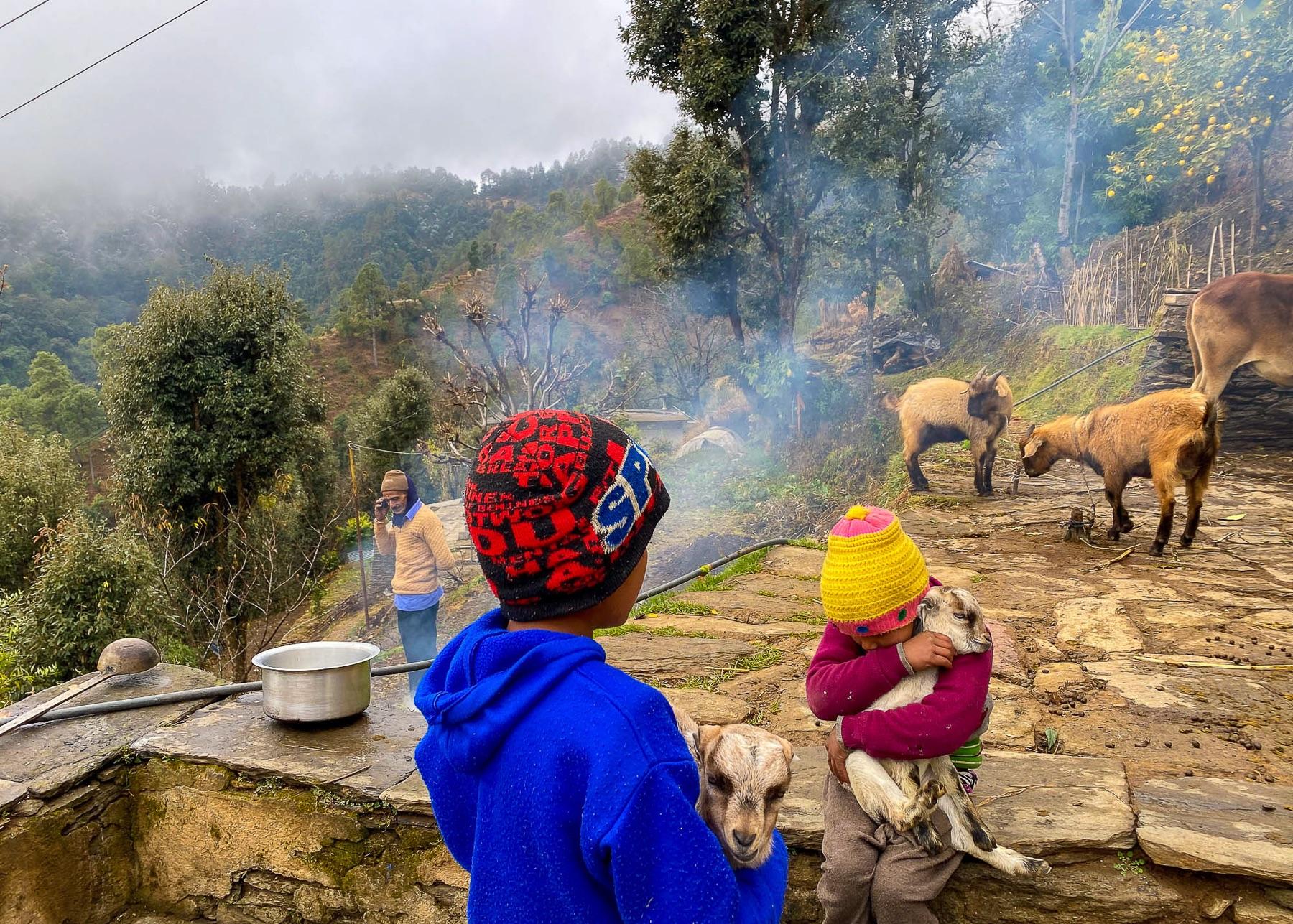 Children and an elder by the fire — generations of family life at Kunja